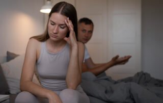 Retrato panorámico de Fabi Herra y sus dos hijas, Sofi y Lucía, sonriendo juntas en un banco de madera en un jardín al aire libre.