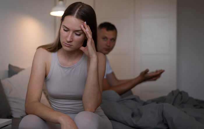 Retrato panorámico de Fabi Herra y sus dos hijas, Sofi y Lucía, sonriendo juntas en un banco de madera en un jardín al aire libre.